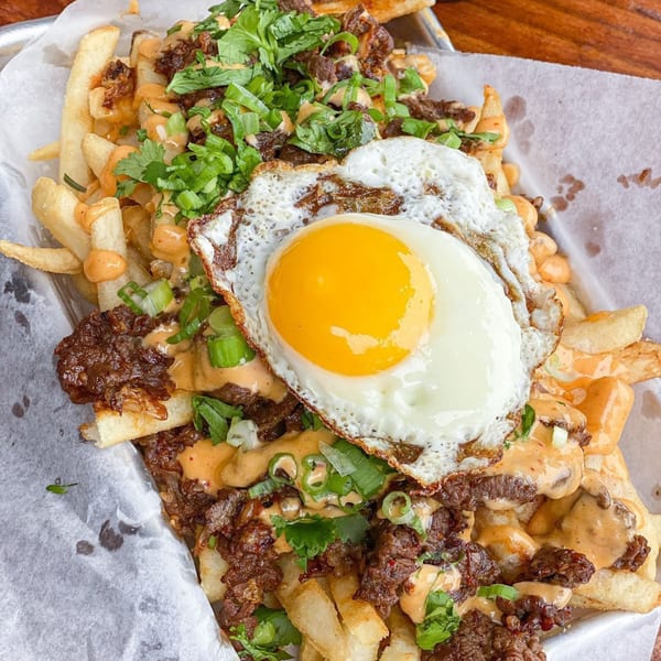 Banh Mi Boys' loaded fries with bulgogi, spicy mayo, cilantro, green onions, and a fried egg.